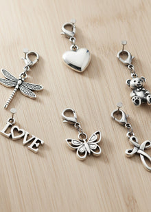 Collection of silver charms on a wooden surface
